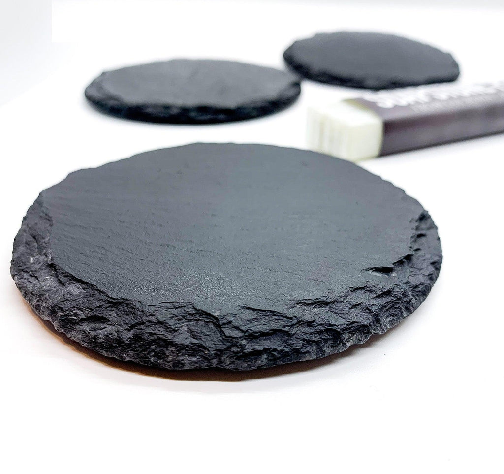 Close-up of a natural slate coaster showing the detailed chiseled edges and dark grey stone texture on a white background.