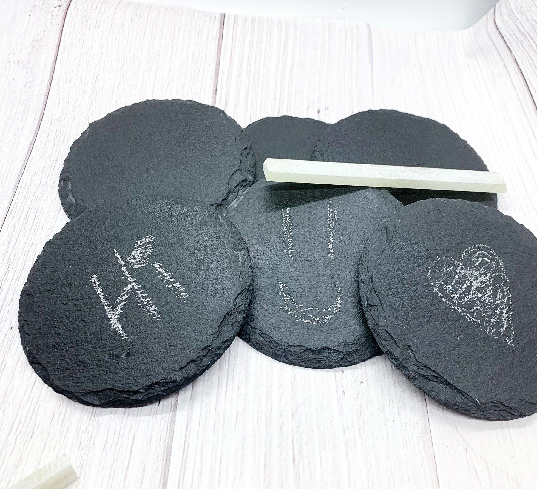 Natural slate coasters shown with a white soapstone chalk pencil to demonstrate how customers can customize each piece with names or labels for a personalized home bar experience.
