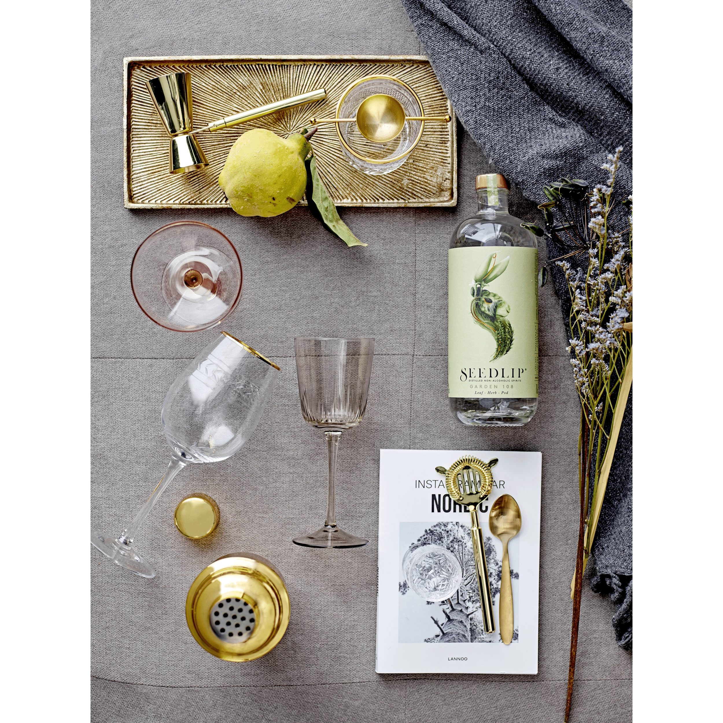 Elegant stainless steel cocktail shaker with a brass finish, styled on a dark rustic bar for the perfect home cocktail experience.