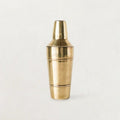 Stainless steel cocktail shaker with brass finish on a dark background.